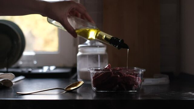 young housewife marinates meat in olive oil and spices