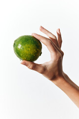 Person holding a green lime in their hand, with a white background