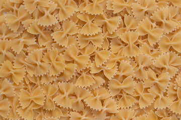 Background image of farfalle. A large pile of yellow farfalle.