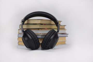 Black headphones placed on a stack of books symbolizing the concept of audio learning and education...
