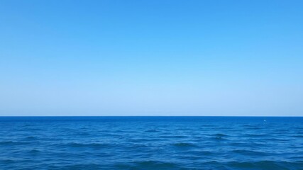Obraz premium A serene ocean background with crystal clear blue water, gentle waves, and a cloudless sky, landscape, ocean