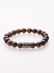 A charming double bracelet in shades of pink, made from natural stone and set against a gray background. The heart charm with cubic zirconia stands out in this close-up top view