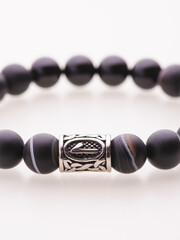 A charming double bracelet in shades of pink, made from natural stone and set against a gray background. The heart charm with cubic zirconia stands out in this close-up top view