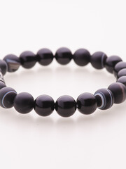 A charming double bracelet in shades of pink, made from natural stone and set against a gray background. The heart charm with cubic zirconia stands out in this close-up top view