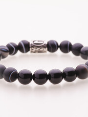 A charming double bracelet in shades of pink, made from natural stone and set against a gray background. The heart charm with cubic zirconia stands out in this close-up top view