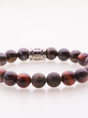 A charming double bracelet in shades of pink, made from natural stone and set against a gray background. The heart charm with cubic zirconia stands out in this close-up top view