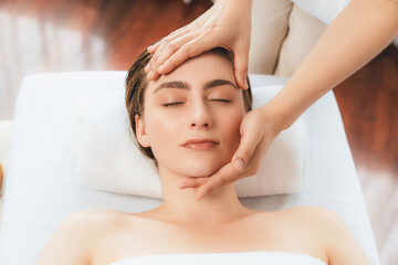 Naklejka premium Caucasian woman enjoying relaxing anti-stress head massage and pampering facial beauty skin recreation leisure in dayspa modern light ambient at luxury resort or hotel spa salon. Quiescent