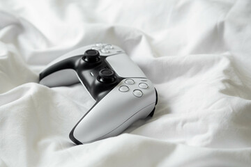 Game controller, lying on white sheets of bed at home. © sav_an_dreas
