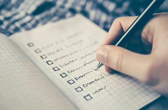 A person is writing on their to-do list, with checkboxes and handwritten...