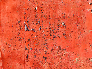 A vibrant red wall shows signs of wear, featuring peeling paint and an uneven texture, perfect for adding character to any design