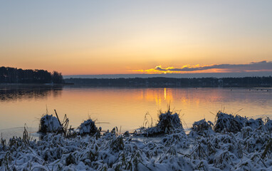 A wonderful view of a lake frozen by the shore at sunset. Great colorful sky with sun. Latvia. Baltezers