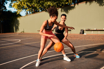 Obraz premium Fun, basketball and women playing game together for competition, challenge and fitness on playground. Outdoor, performance and girl friends on court with ball, exercise and teamwork at sports club.