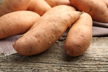 Fresh raw sweet potatoes on wooden table, closeup