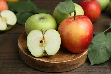 Different ripe apples on wooden table, closeup