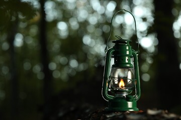 Vintage kerosene lamp in forest at evening, space for text