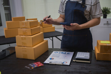 An Asian man carefully prepares a package for a customer's online order, methodically placing items in a box, sealing it securely, and attaching a shipping label for prompt delivery.