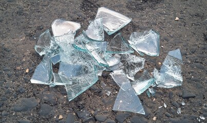 Shattered glass pieces on asphalt.