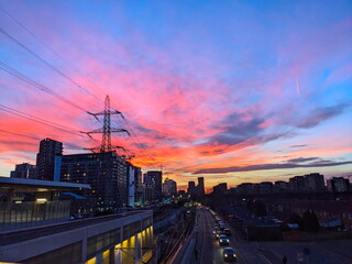 London, UK - 02.01.2024: Evening glow over Custom House Elizabeth Line and Docklands Light Railway station alongside cars queuing before a red light 