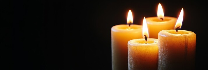 Burning candles emitting warm light in the darkness. Copy space for text