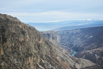 A blue river flows through the canyon. The landscape is dry, without any vegetation, the season is winter. The water is calm and peaceful.