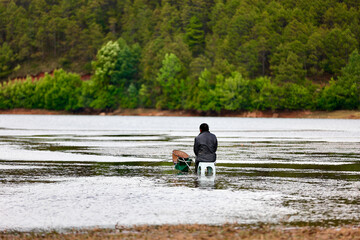 fishing man sitting beside the lake near the mountain