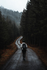 Woman walking on moody road in rainy forest
