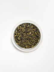 Top view of green tea leaves in a glass cup isolated on  white background. Milk oolong tea. 