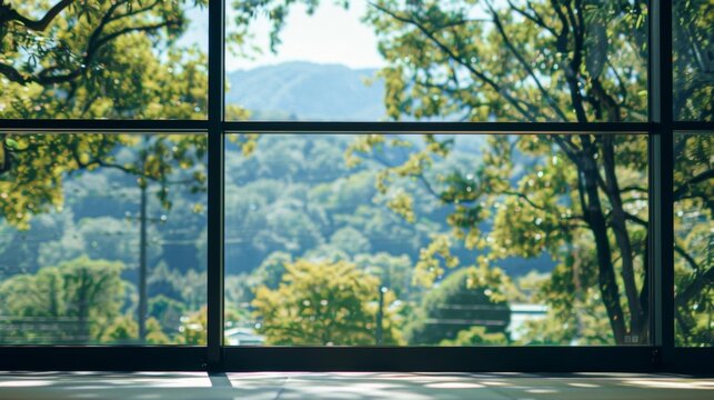 Fototapeta Sunlight is streaming through a large window overlooking a green forest and blue sky. The sunlight casts shadows on the floor