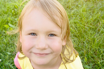 Close up of face of child girl looking at camera with happy smile on summer sunny day