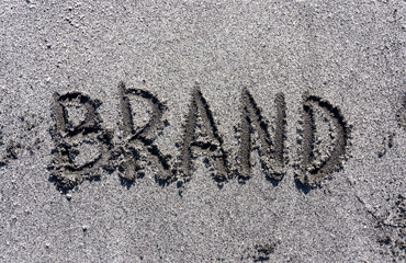 Fototapeta premium Business brand concept. Concept word brand written on beautiful ocean sand beach. Beautiful ocean sand beach background, copy space. Business brand concept.