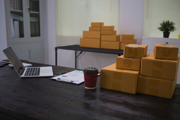 An Asian man carefully prepares a package for a customer's online order, methodically placing items...