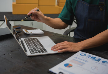 An Asian man carefully prepares a package for a customer's online order, methodically placing items in a box, sealing it securely, and attaching a shipping label for prompt delivery.