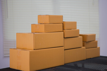 An Asian man carefully prepares a package for a customer's online order, methodically placing items in a box, sealing it securely, and attaching a shipping label for prompt delivery.