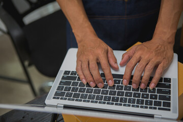 An Asian man carefully prepares a package for a customer's online order, methodically placing items in a box, sealing it securely, and attaching a shipping label for prompt delivery.