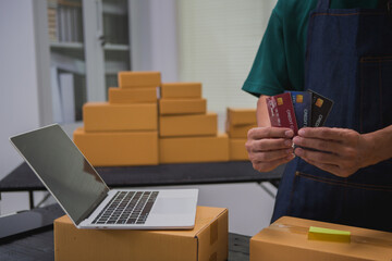 An Asian man carefully prepares a package for a customer's online order, methodically placing items in a box, sealing it securely, and attaching a shipping label for prompt delivery.