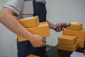 An Asian man carefully prepares a package for a customer's online order, methodically placing items...