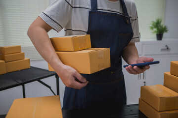 An Asian man carefully prepares a package for a customer's online order, methodically placing items...