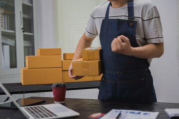 An Asian man carefully prepares a package for a customer's online order, methodically placing items...