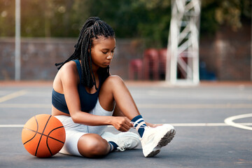 Black woman, basketball and tying shoes at court for exercise, training and beginning of game. Player, fitness and athlete with footwear on ground for sports competition, start or match preparation
