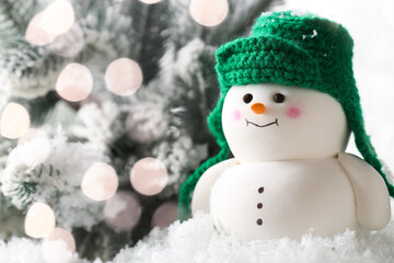 Cute decorative snowman and fir tree branches on artificial snow against white background, closeup