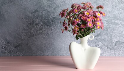 Stylish vase with beautiful flowers on pink wooden table. Space for text