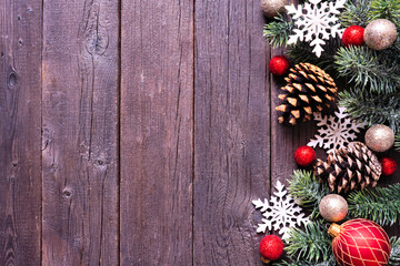 Christmas side border of red and gold baubles, snowflakes, pinecones and frosty branches. Overhead view on a dark wood background. Copy space.