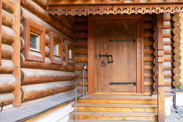 Carved wooden porch with steps in an authentic log home with windows