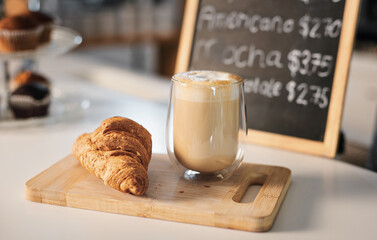 Coffee, croissant and breakfast on board in cafe for sweet treat and caffeine in morning. Cappuccino, baked goods and restaurant with latte and fresh gourmet french pastry for dessert or snack.