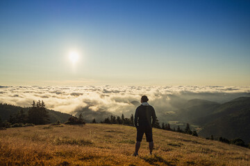 Randonneur contemplatif observant le lever du Soleil sur les nuages dans le calme des Pyrénées - France