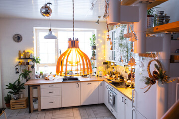 Christmas decor in white kitchen, modern village interior with a snowy Christmas tree and fairy lights. New Year, Christmas mood, cozy home, Metal modular staircase.