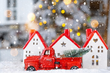 Key on Christmas tree and tiny house with a red roof with Christmas decor in red retro car on table . Gift for New Year. Insurance, moving to new house, mortgage, rent and real estate