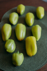 Green bell peppers arranged on a woven green placemat in a kitchen setting, showcasing fresh produce, perfect for food preparation, cooking, or healthy eating concepts, emphasizing natural ingredients