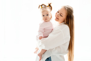a mother with a baby daughter, a mother gently hugs her baby girl kissing, maternal love and care, a happy family with a baby on a white isolated background, a place for text
