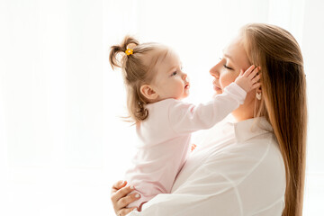 a mother with a baby daughter, a mother gently hugs her baby girl kissing, maternal love and care, a happy family with a baby on a white isolated background, a place for text